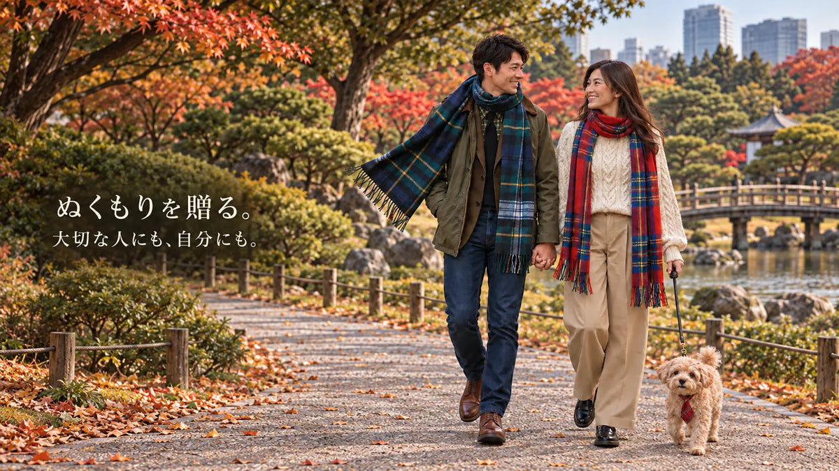 ぬくもりを贈る。大切な人にも、自分にも。ディアゲヨーネのマフラーコレクション。チェック柄のマフラーを巻いた男女が、愛犬ルクと秋の公園を歩く。