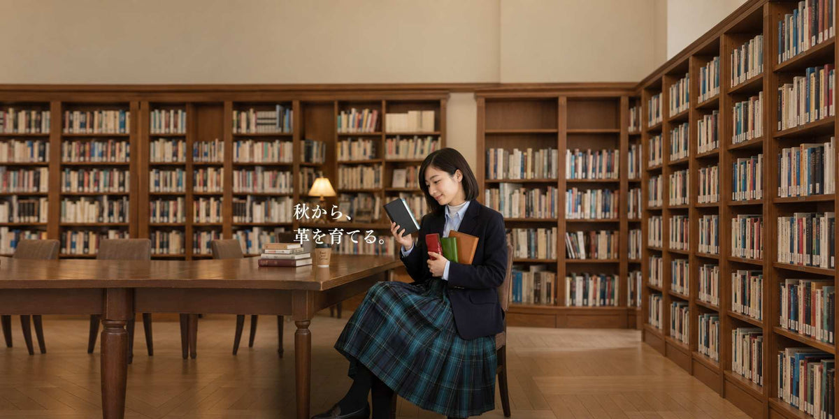 図書館で革のシステム手帳を手に取る女性｜秋から育てるレザーアイテム